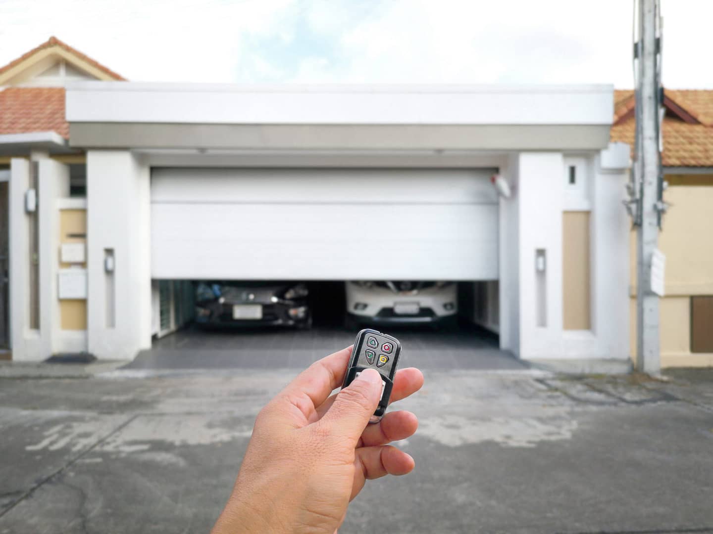 Hand holding a remote control to open a sliding door - demonstrating the use of an electrical, automatic door system.