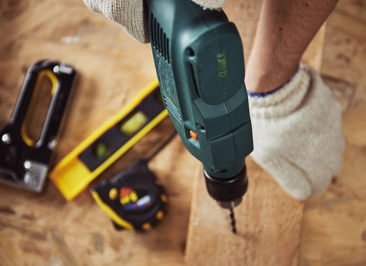 A skilled carpenter using a drilling machine to masterfully craft wood and construct with precision inside a house.