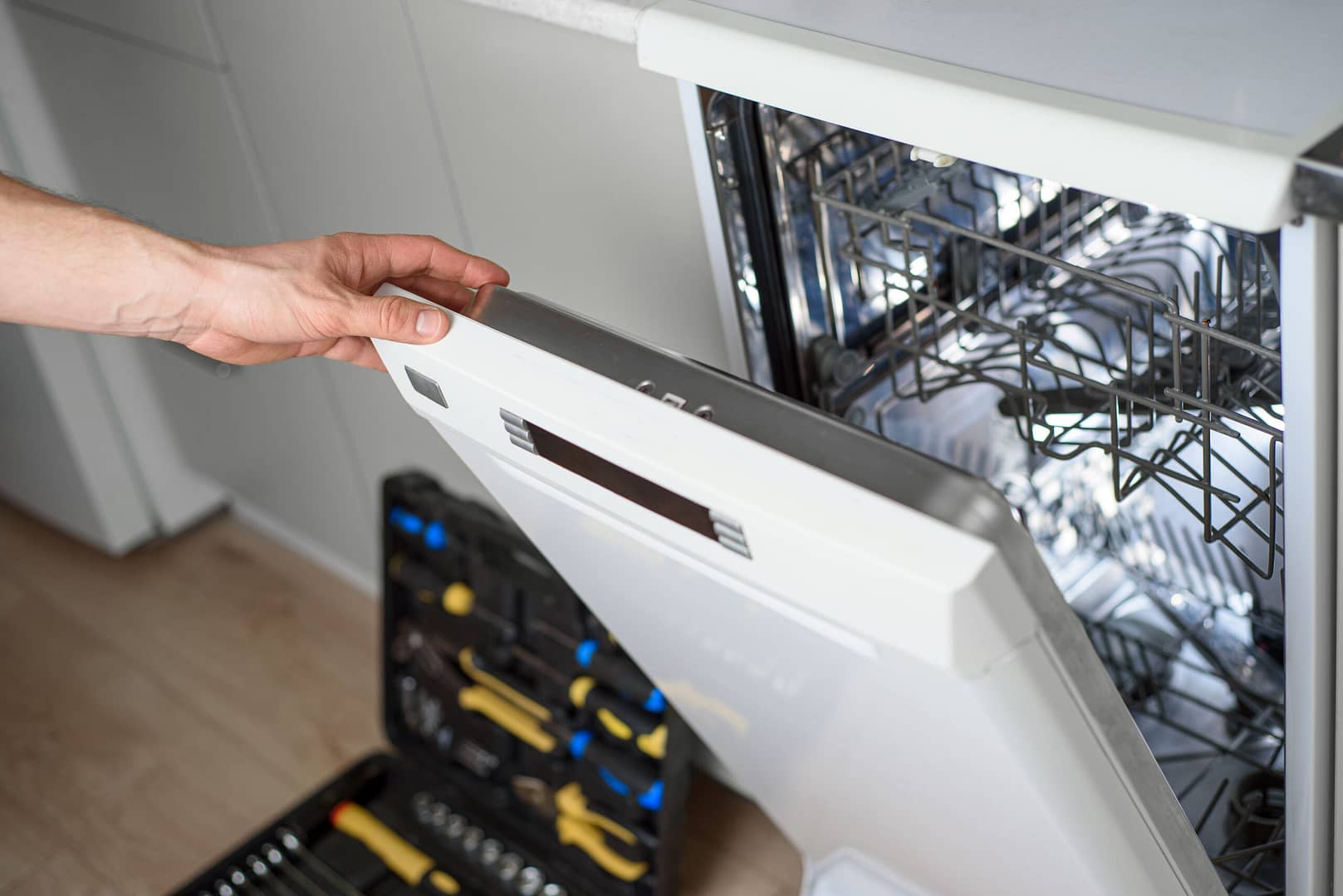 Technician meticulously inspecting a dishwasher, symbolizing expert appliance repair service in action.