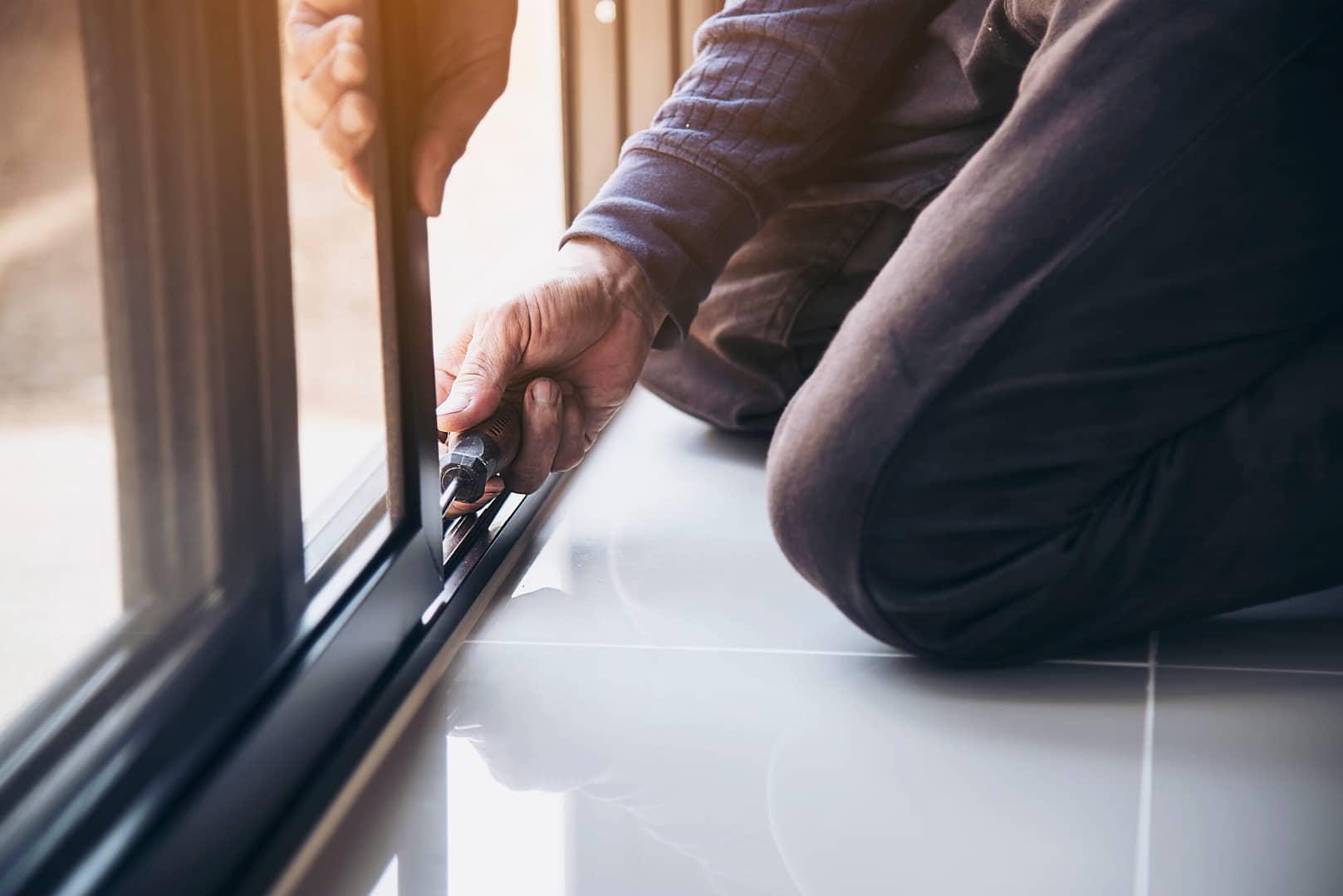 A skilled construction worker wearing safety glasses carefully assembling an aluminum frame for a window installation at a construction site.