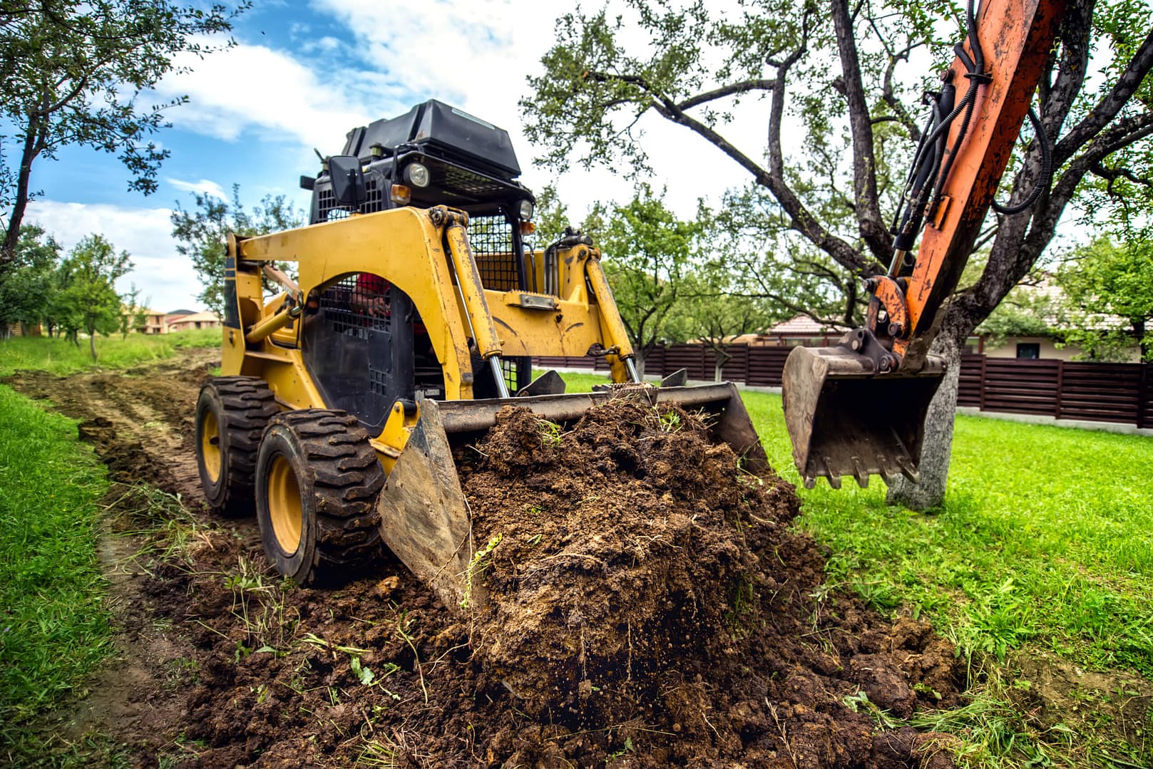 A yellow mini bulldozer hard at work, moving soil and shaping the landscape with precision.