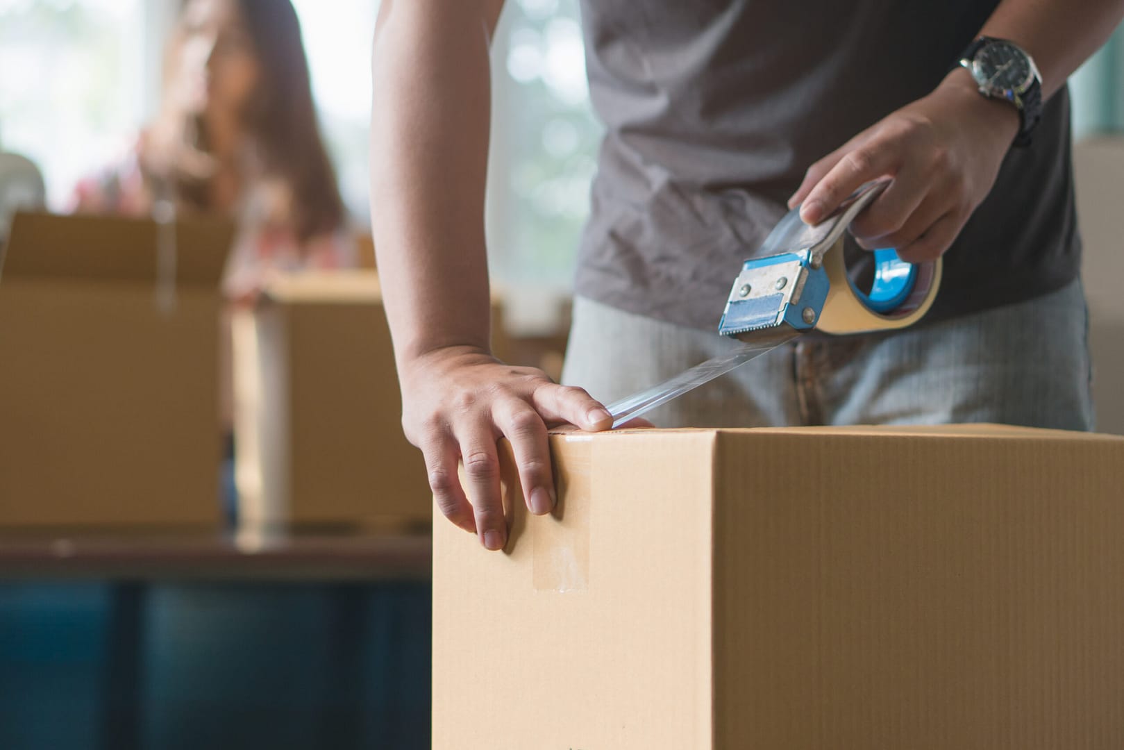 Mover securely sealing a box for transport – Underlining the meticulous attention to detail in moving company operations.