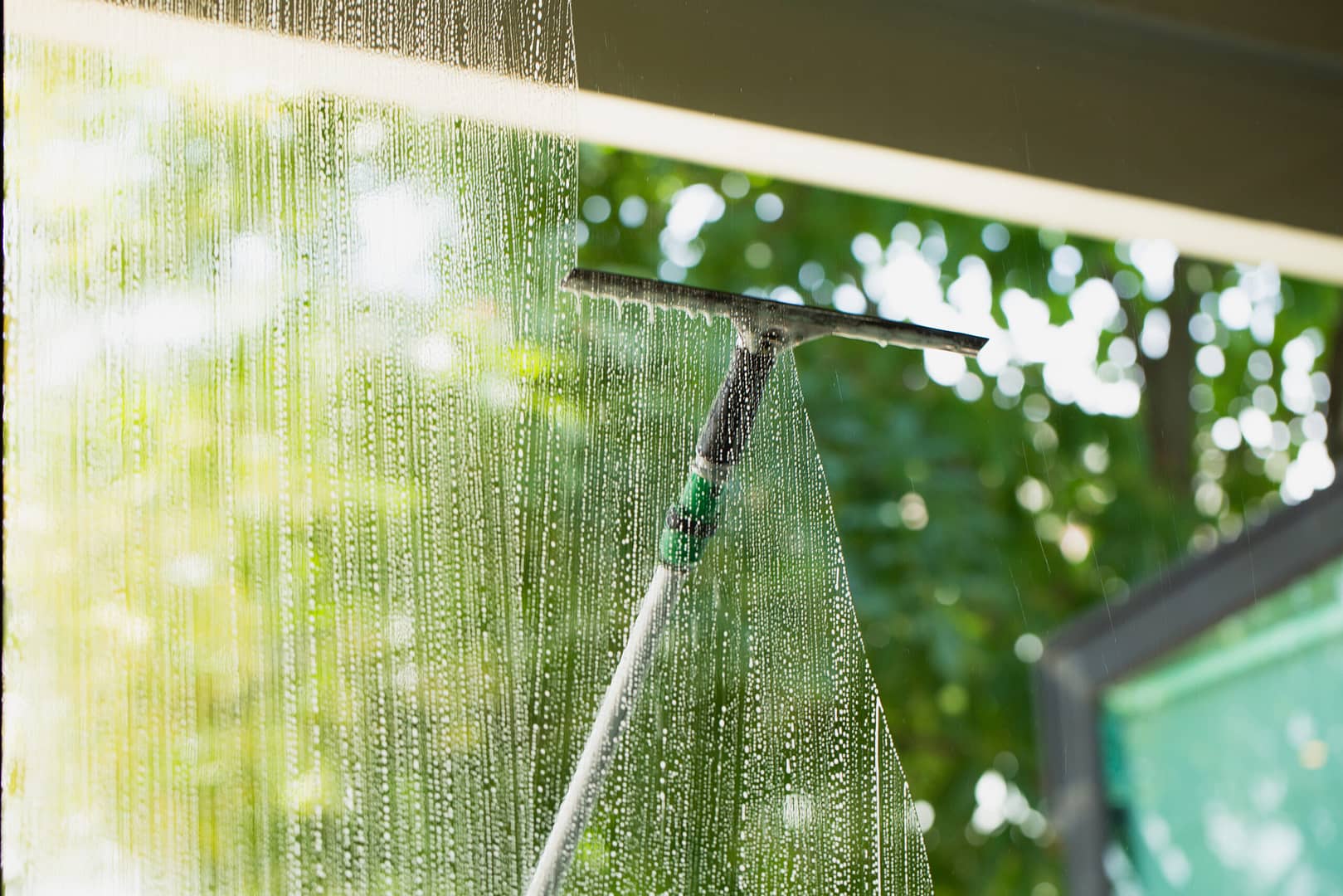 Long-handled squeegee on a sliding glass door, highlighting the tools and expertise promoted in our window cleaning marketing campaigns.