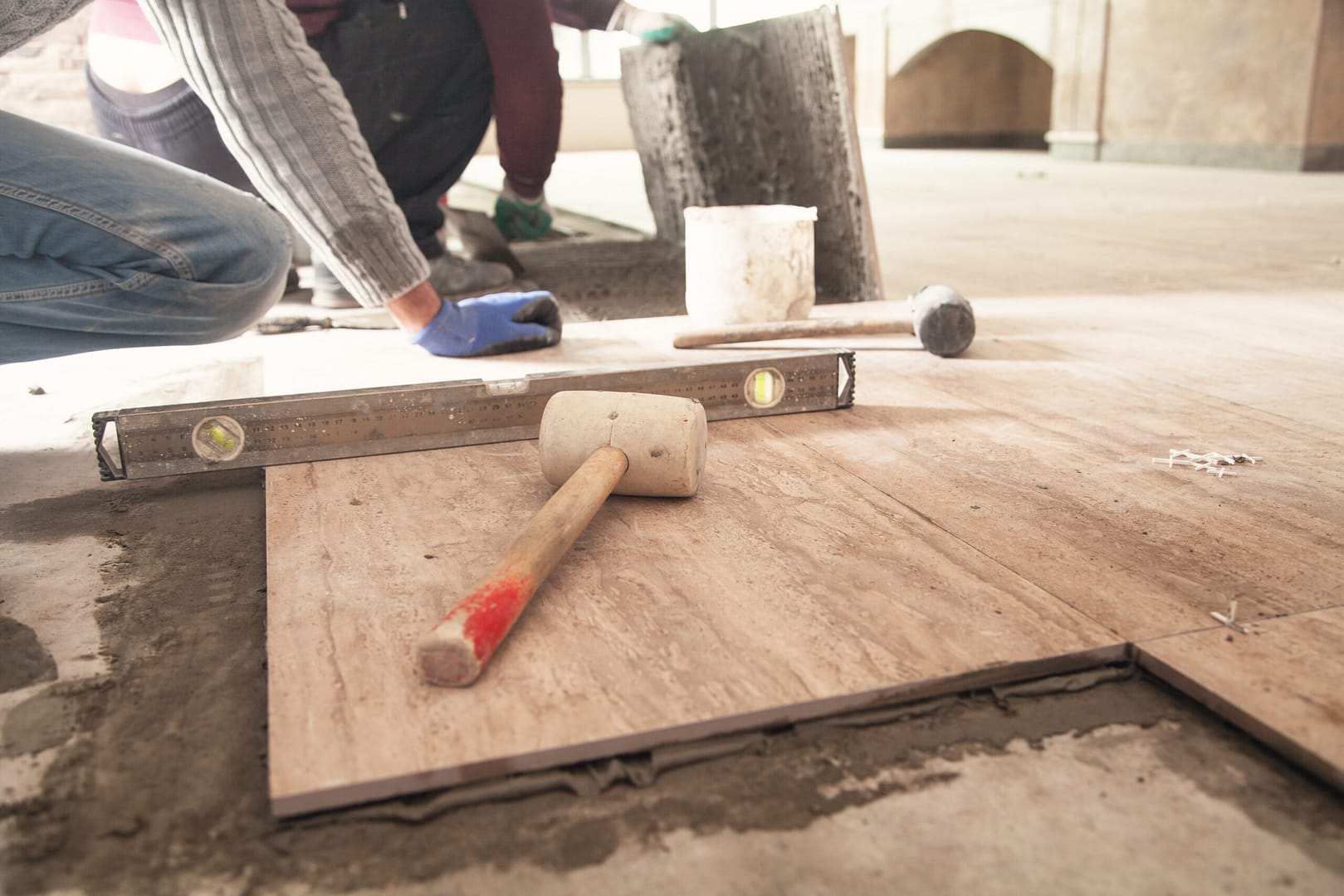 Renovating the floor with ceramic tiles: A worker carefully lays down ceramic floor tiles in a neat, precise pattern.