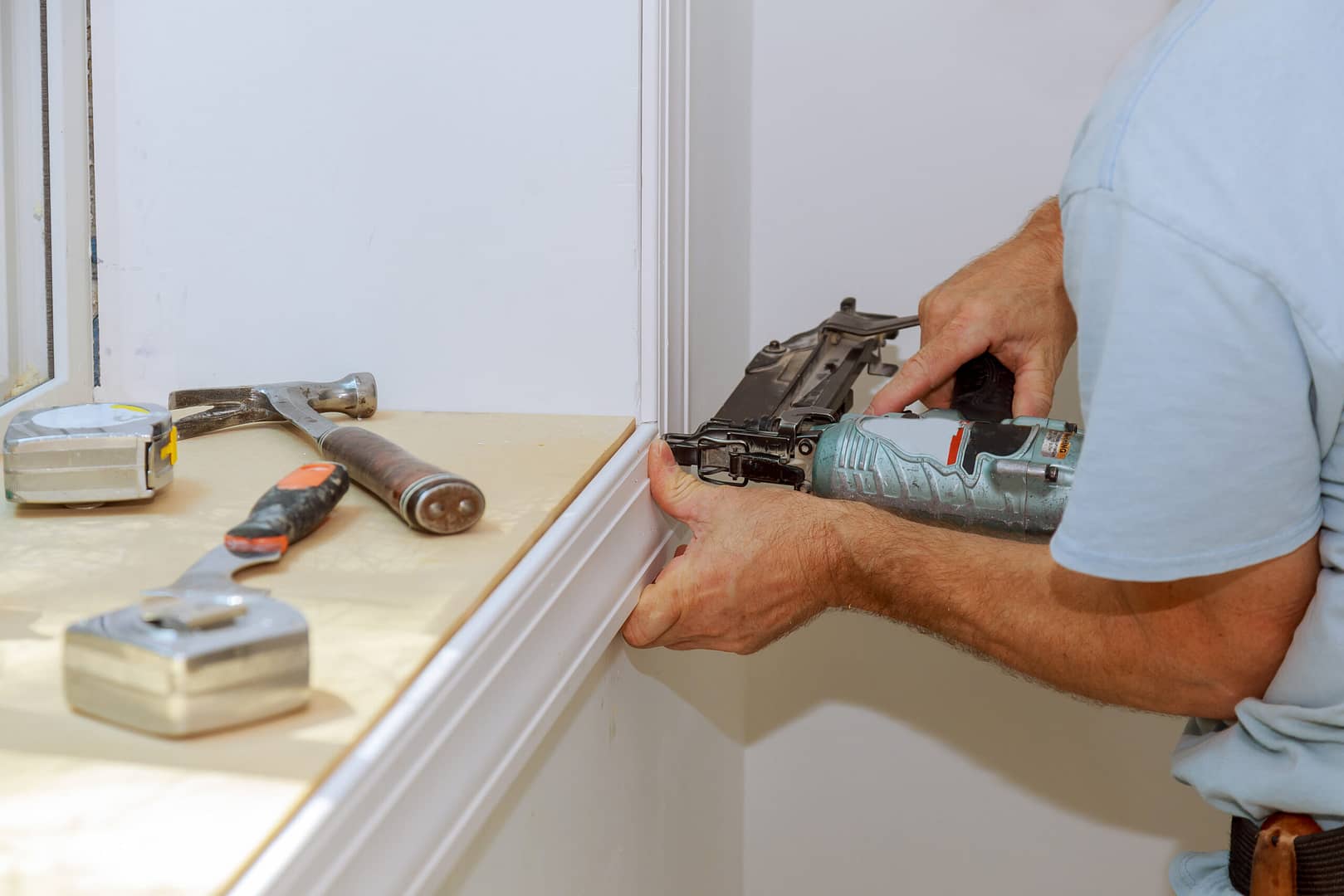 A worker carefully installing trim around a window with precision and attention to detail.