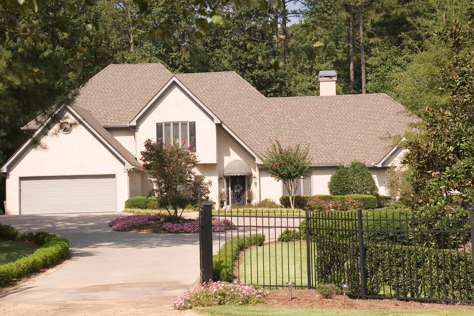 Stunning house with a gracefully landscaped garden, nestled behind a charming black fence.