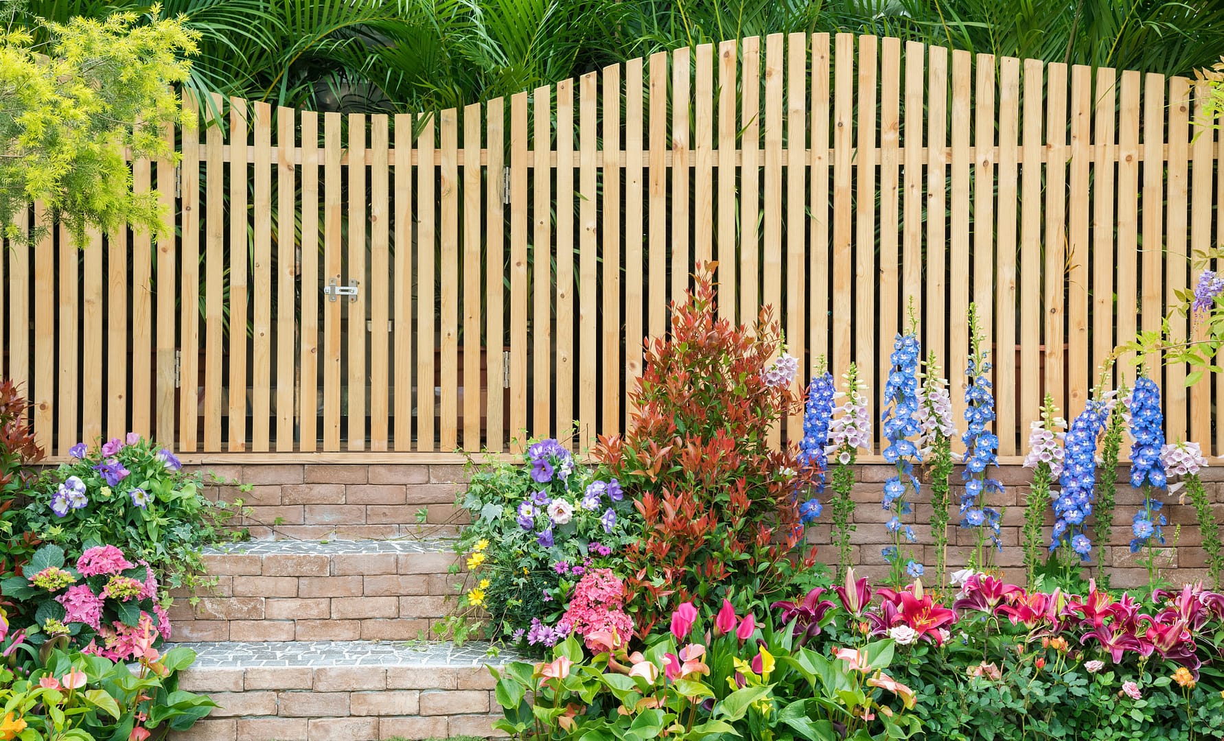 Wooden fence adorned with flowers and complemented by hardscape elements – a testament to the structured yet organic approach of online landscapers marketing.