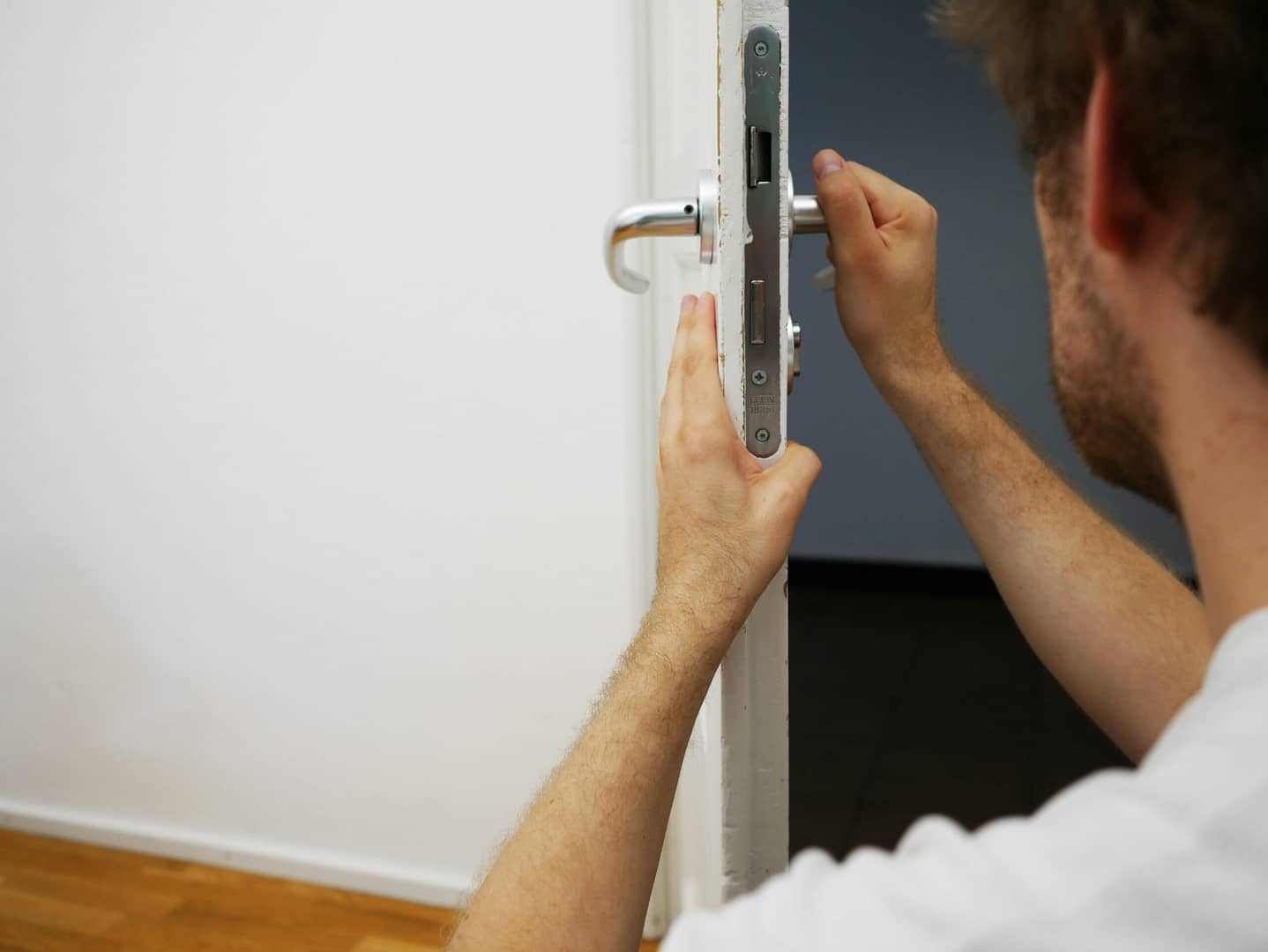 A man carefully adjusts a door mechanism to prevent accidental lockouts.