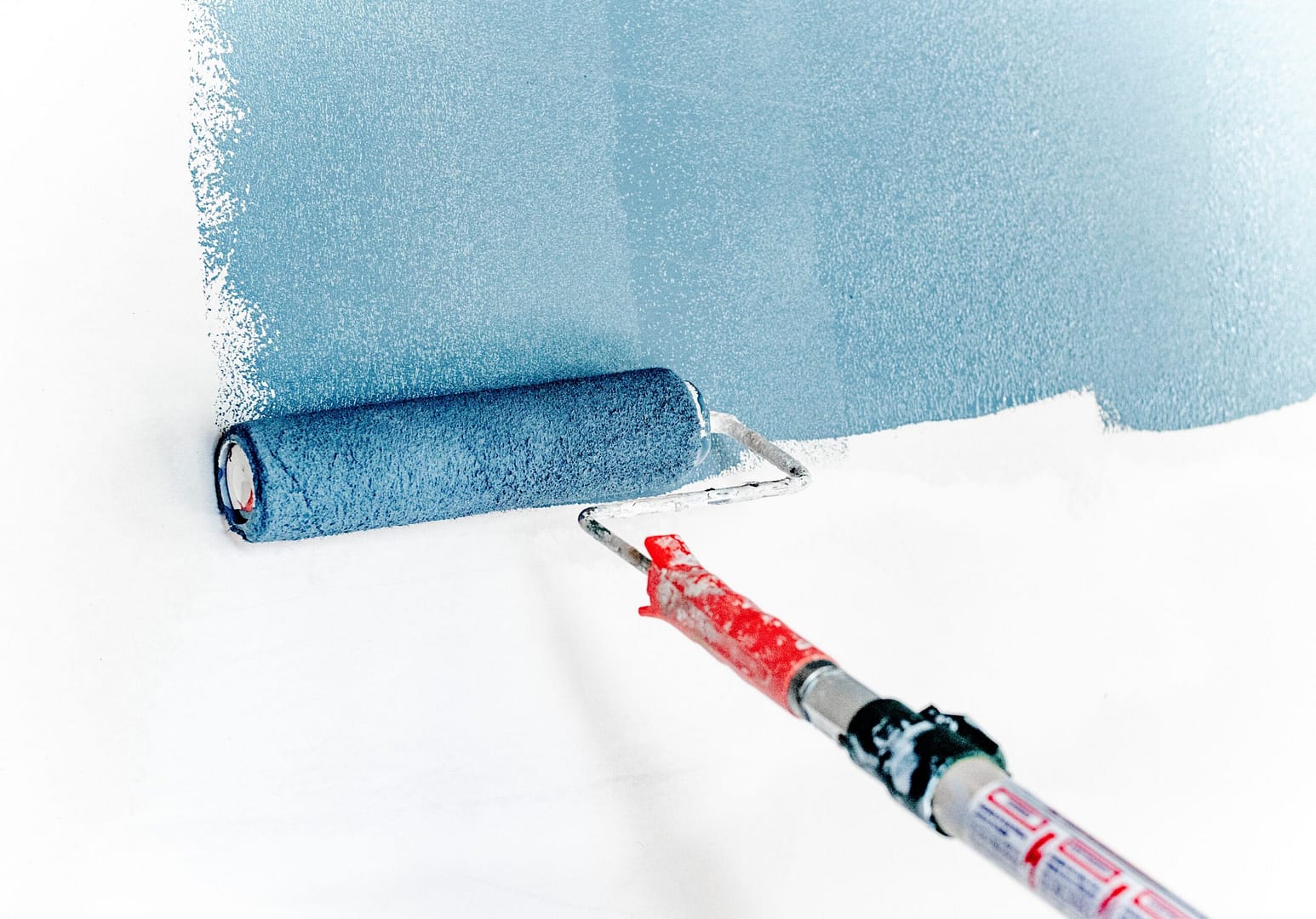 Applying a soothing shade of blue paint to a wall with a roller brush.