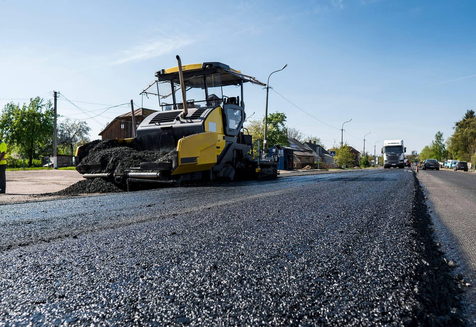 An asphalt paver finisher in action, smoothly laying down a fresh layer of asphalt on the road.