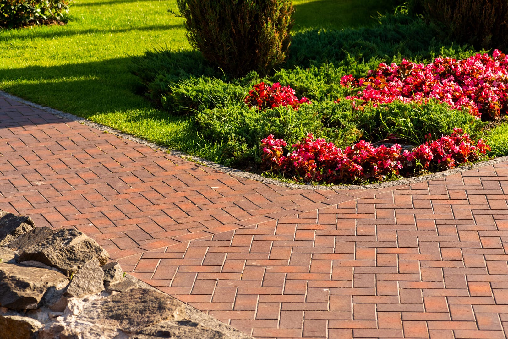 Cobblestone pathway edged by a meticulously manicured garden of flowers and grass – showcasing the precision that digital landscapers marketing brings to targeting the right audience.