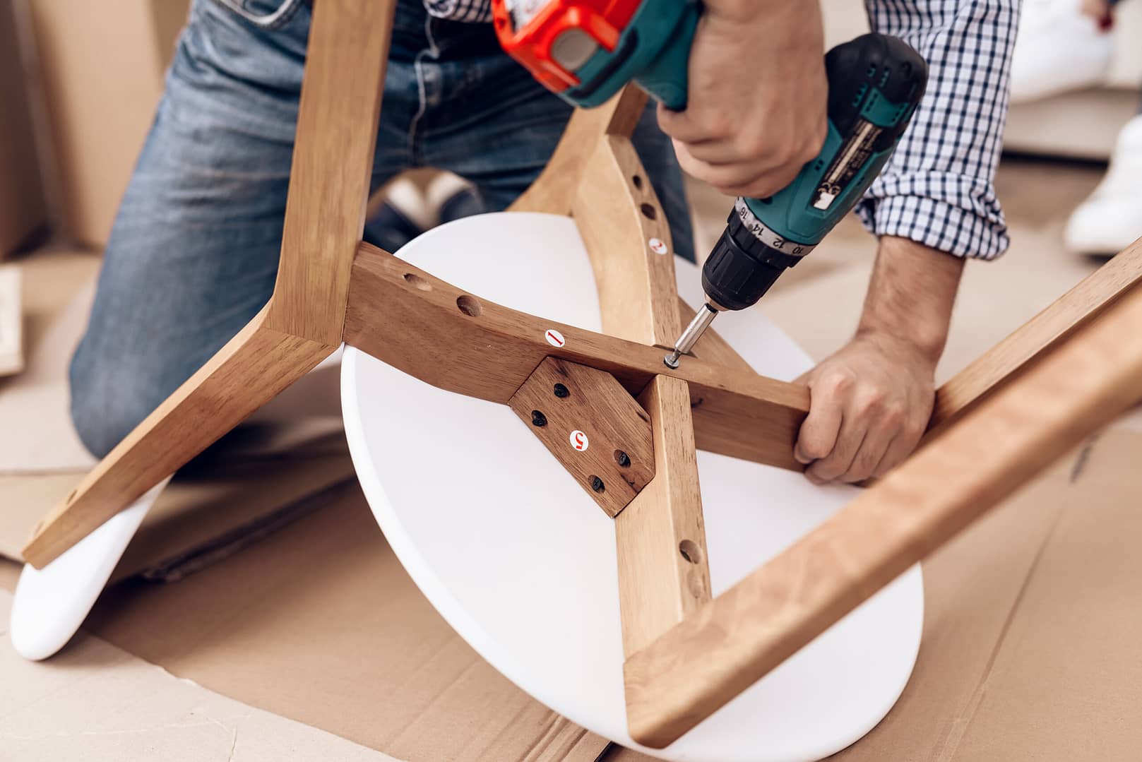 A handyman is assembling a chair, carefully joining its parts together.