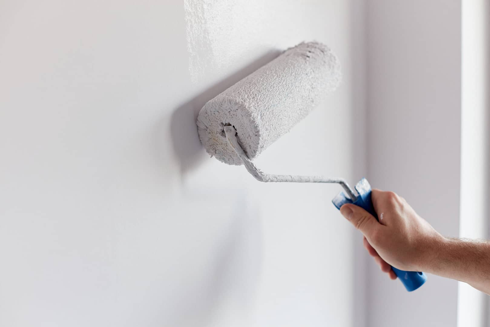 Closeup of a roller against a wall, applying a coat of paint. Much like the precision of this paint application, a targeted digital marketing approach ensures your painting contractor services reach the right audience.