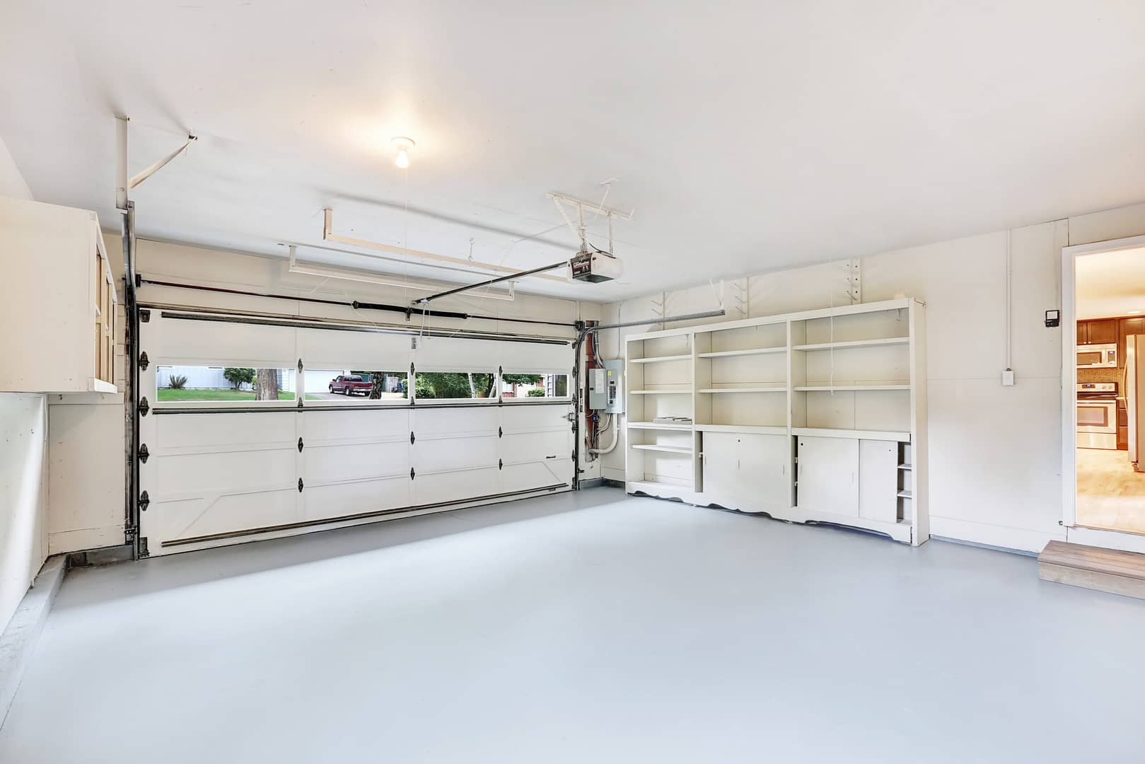 Uncluttered and spacious garage interior in a typical american home, characterized by neatly organized storage shelves and open floor space.