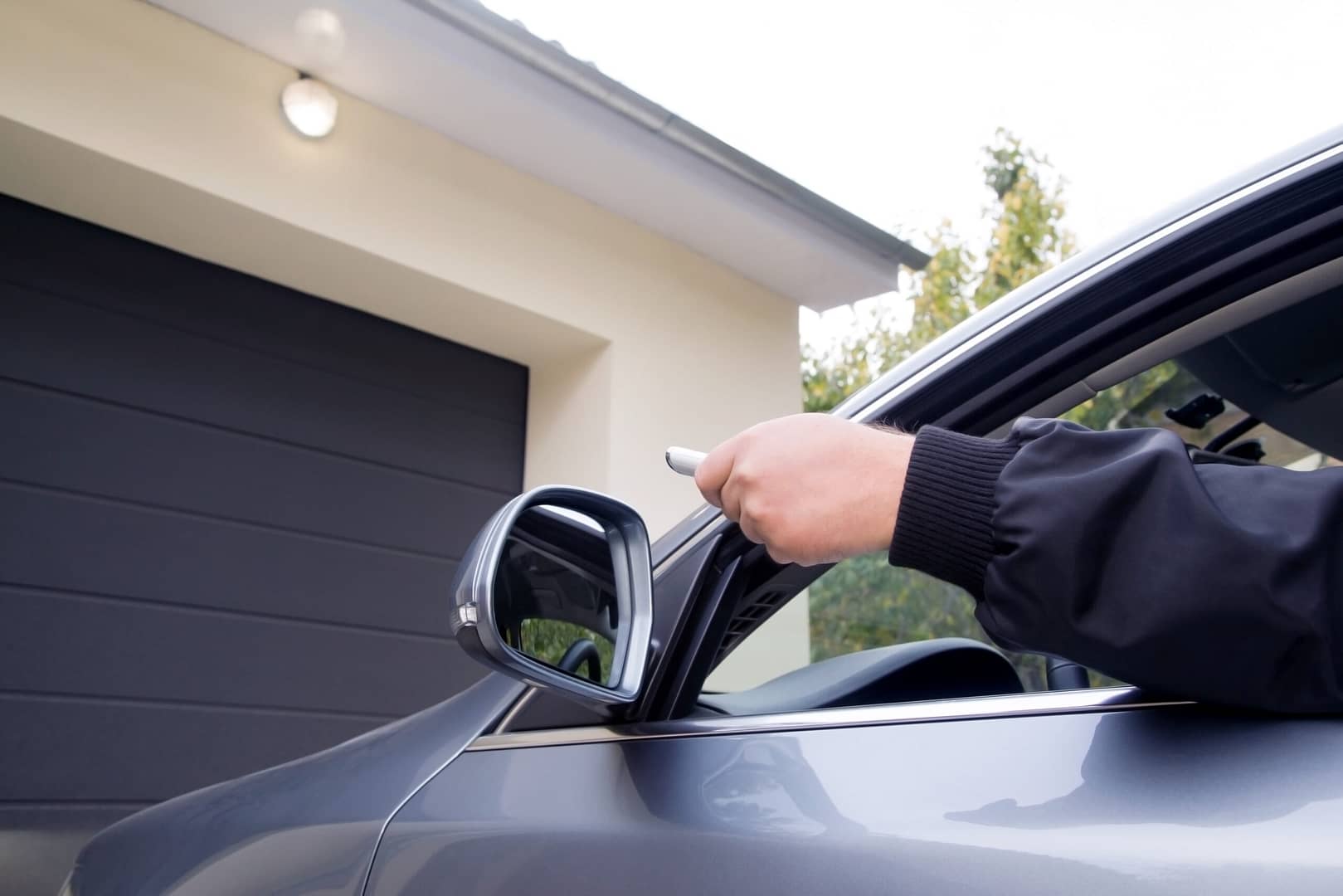 Person using a remote to open the garage door from inside a car.