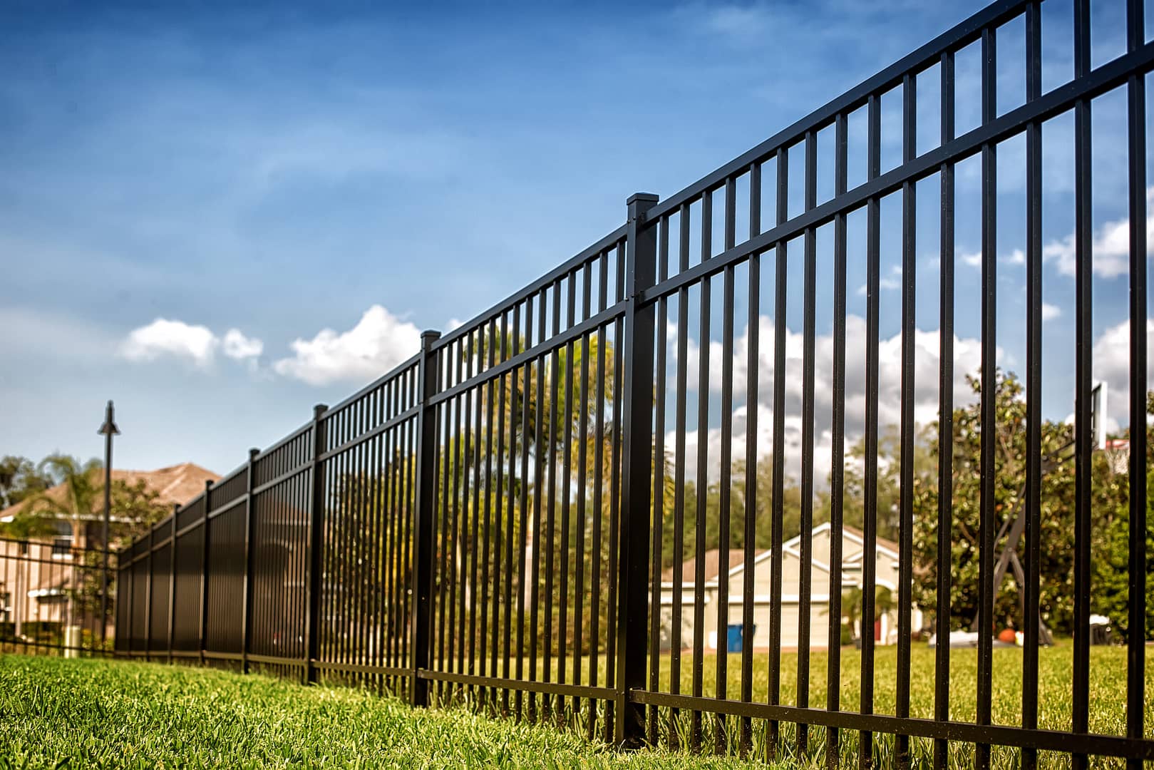 A sleek, black aluminum fence surrounding a well-manicured garden, providing a modern and elegant boundary.