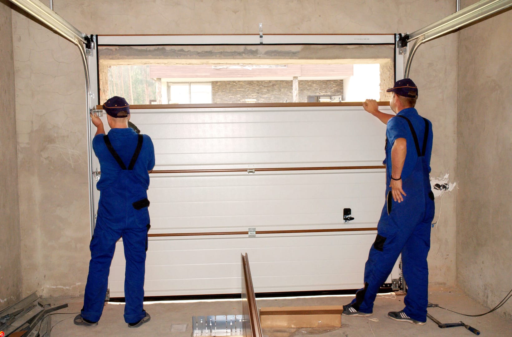 Contractors skillfully installing, repairing, and insulating a garage door with precision and expertise.